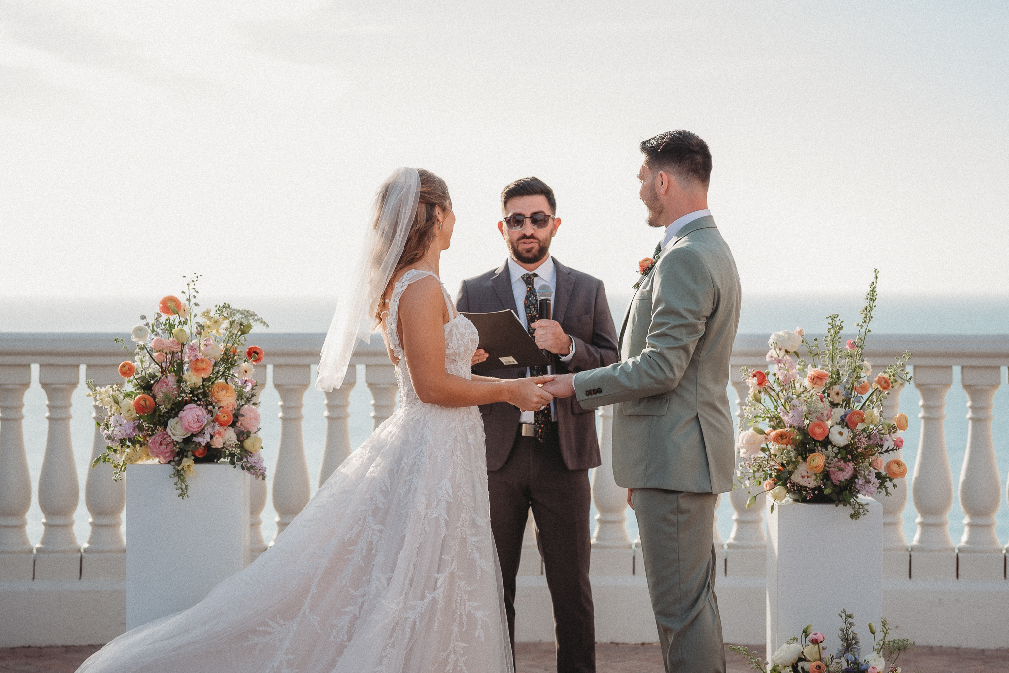 Colorful pastel wedding flowers framing coastal ceremony altar