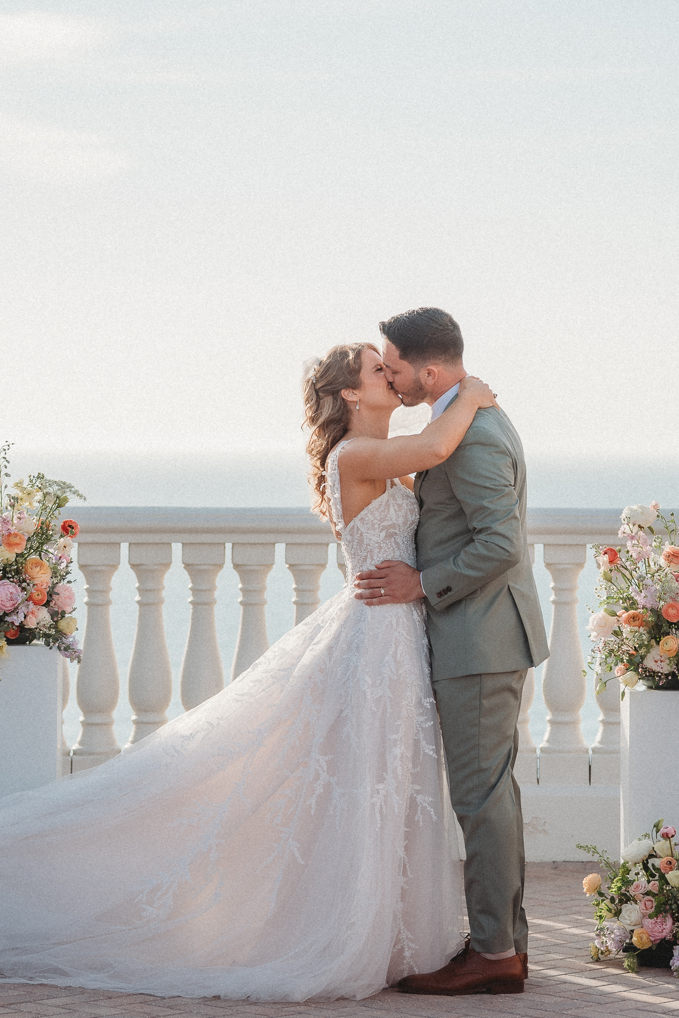 Colorful pastel wedding flowers framing coastal ceremony altar first kiss